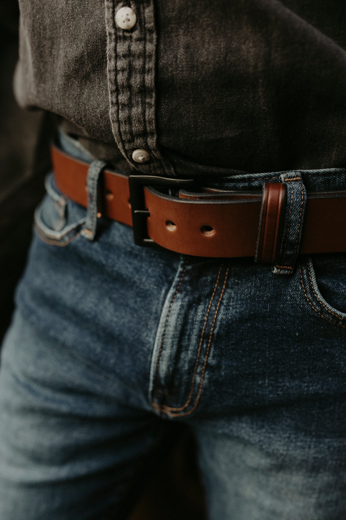 Close-up of blue jeans with a dark shirt tucked in, featuring Hanks Belts’ The Everyday full-grain leather belt.