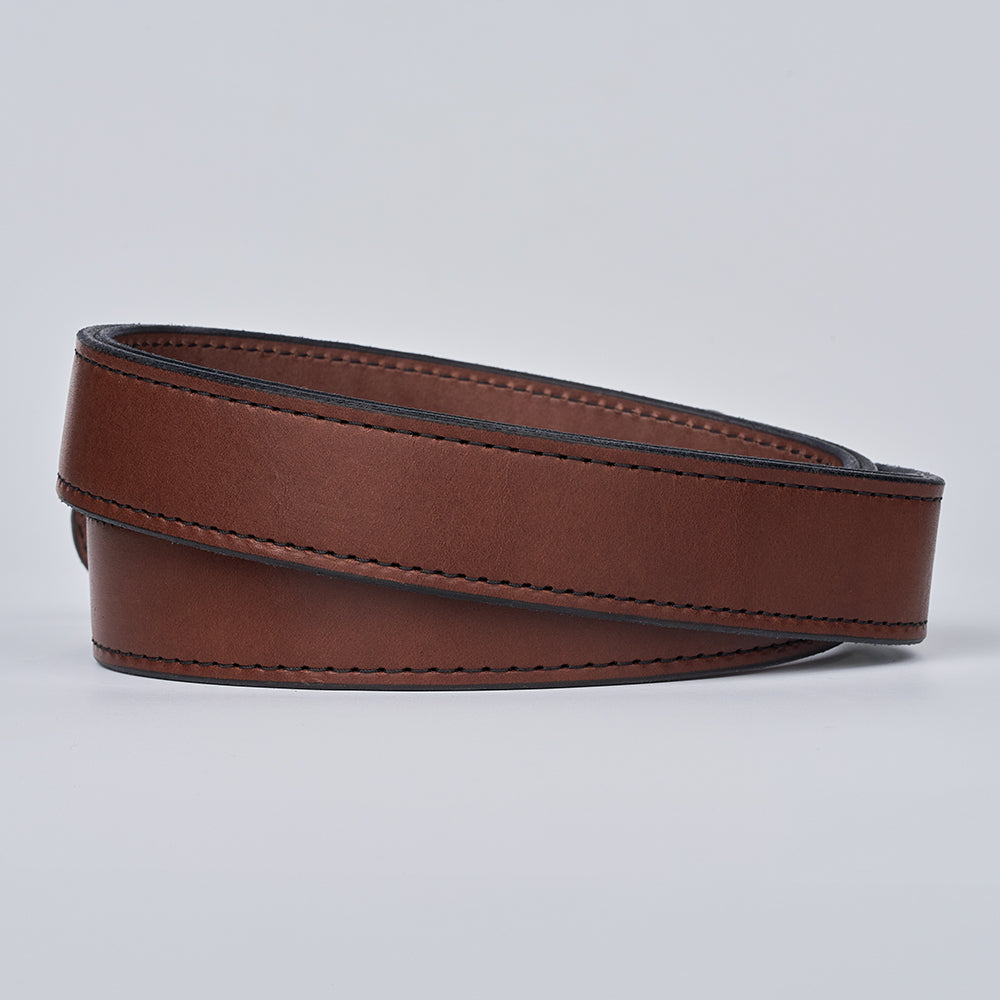 The Steel Core - 1.5" by Hanks Belts is a coiled brown leather CCW gun belt with black edging and visible stitching, shown on a light gray background.