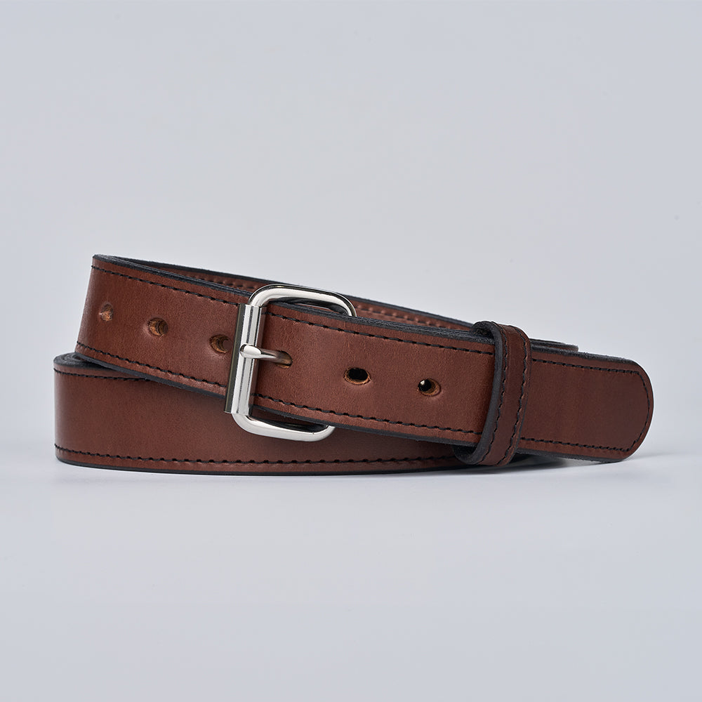 The Hanks Belts Steel Core 1.5" brown leather CCW belt, featuring a silver metal buckle, dark edge stitching, and multiple adjustment holes, is coiled on a plain light gray background—designed for reliable concealed carry use.