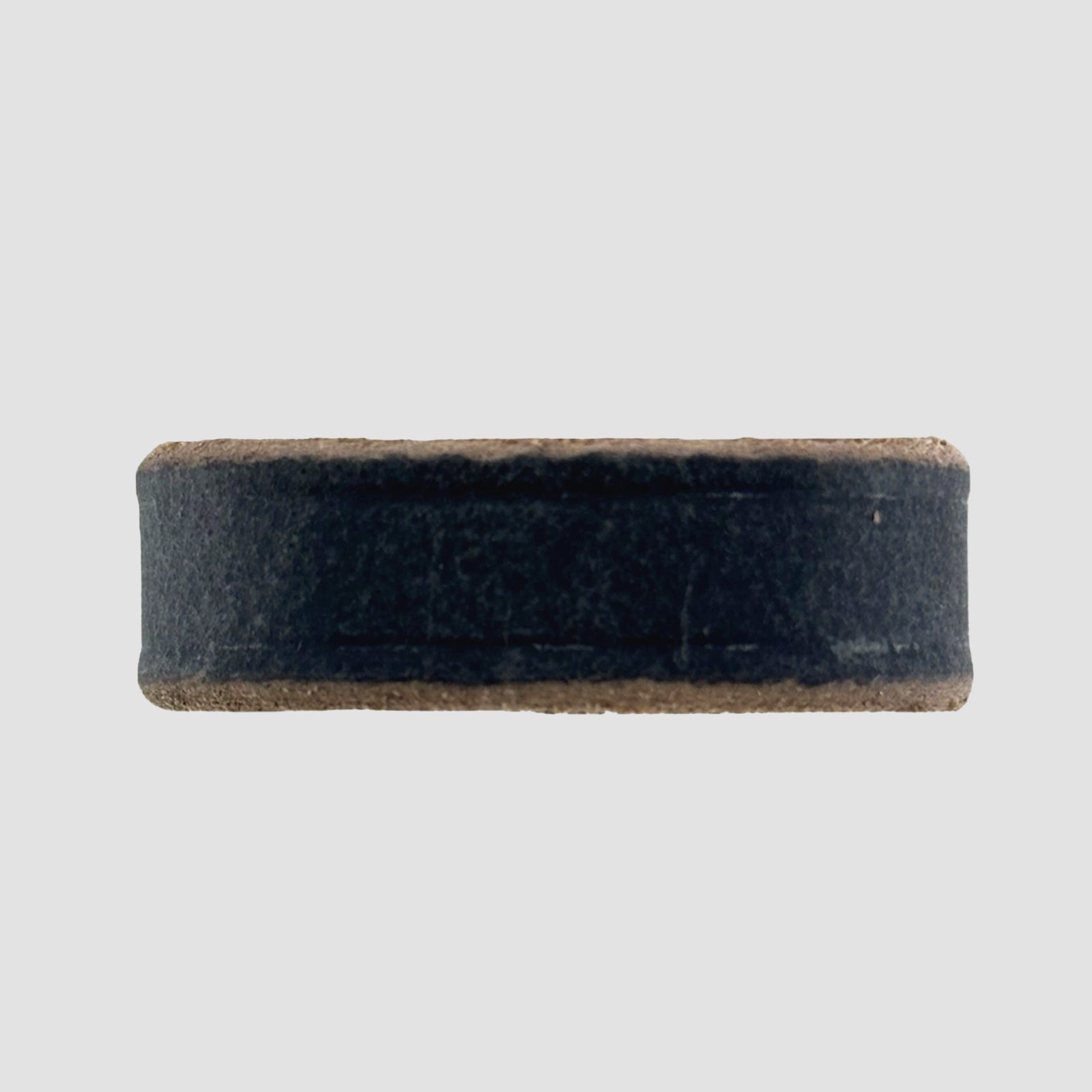 A close-up of a round, flat hockey puck on a white background, its smooth finish and dark color reminiscent of the durable Hanks Belts 1.5" Crazy Horse #9 Keeper.