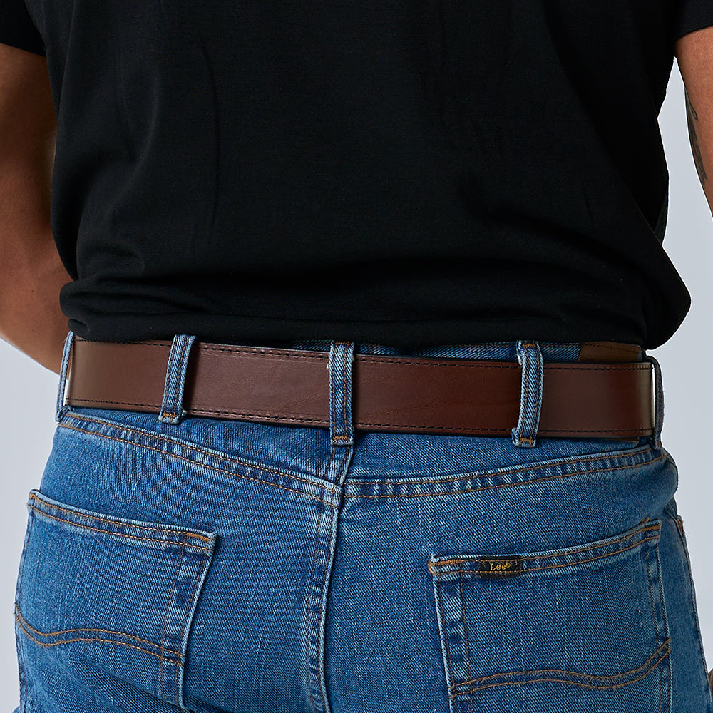 A person is shown from the waist down, back facing the camera, wearing a black shirt, blue jeans, and The Xtreme - 1.75" heavy duty leather work belt by Hanks Belts.